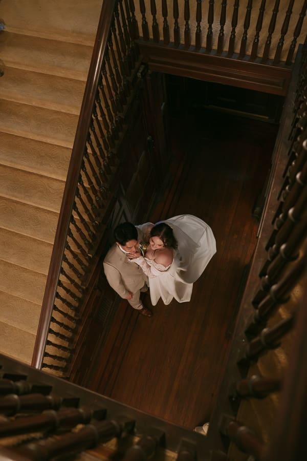 Overhead wedding portrait of the bride and groom embracing on the grand staircase at Gassaway Mansion.