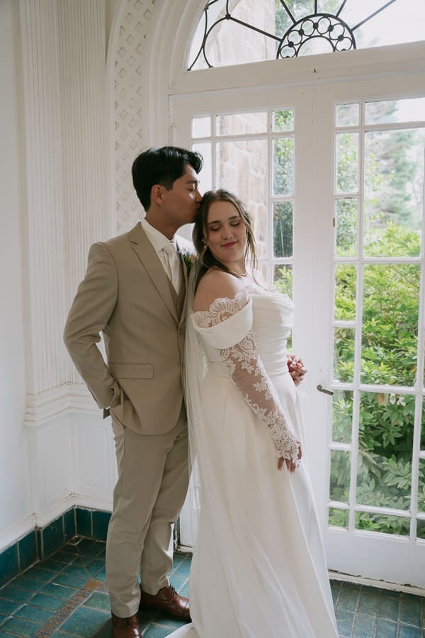 Newly married couple posing beside the tall windows inside Gassaway Mansion.
