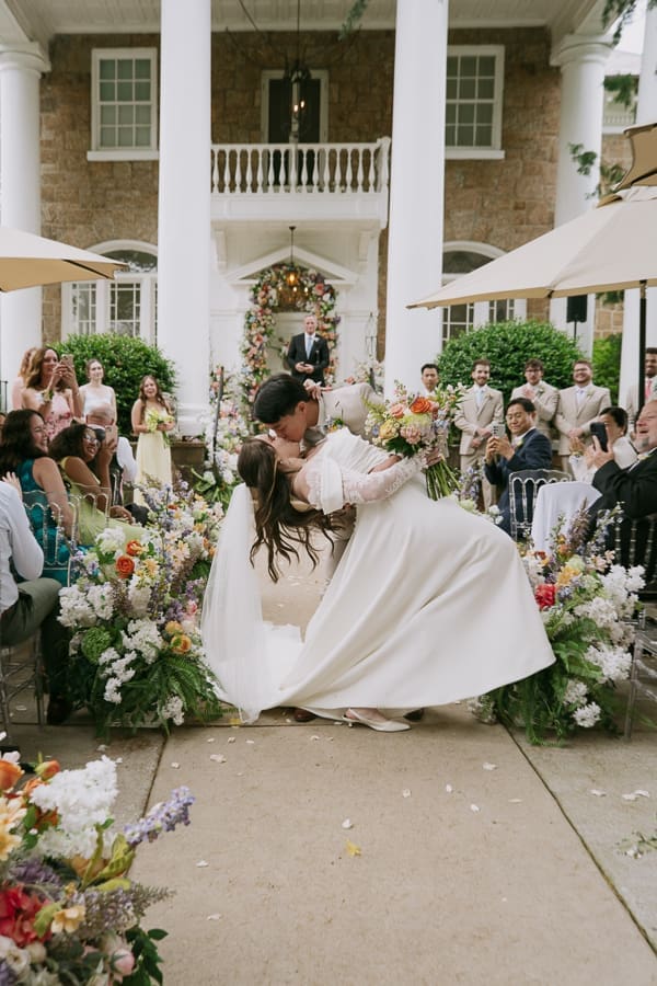 Bride and groom sharing a playful dip after their outdoor wedding ceremony at Gassaway Mansion.