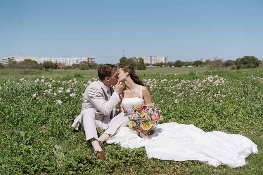 Bride and groom sharing a kiss during wedding portraits among spring wildflowers near Texas A&M University in College Station, Texas.