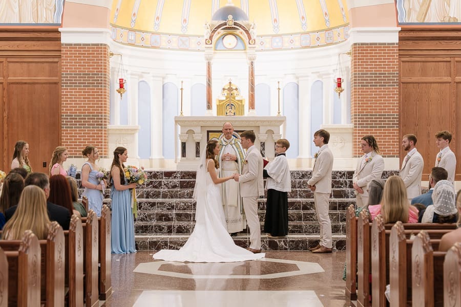 Catholic wedding ceremony with the couple exchanging vows in front of family and friends at a church in College Station, Texas.