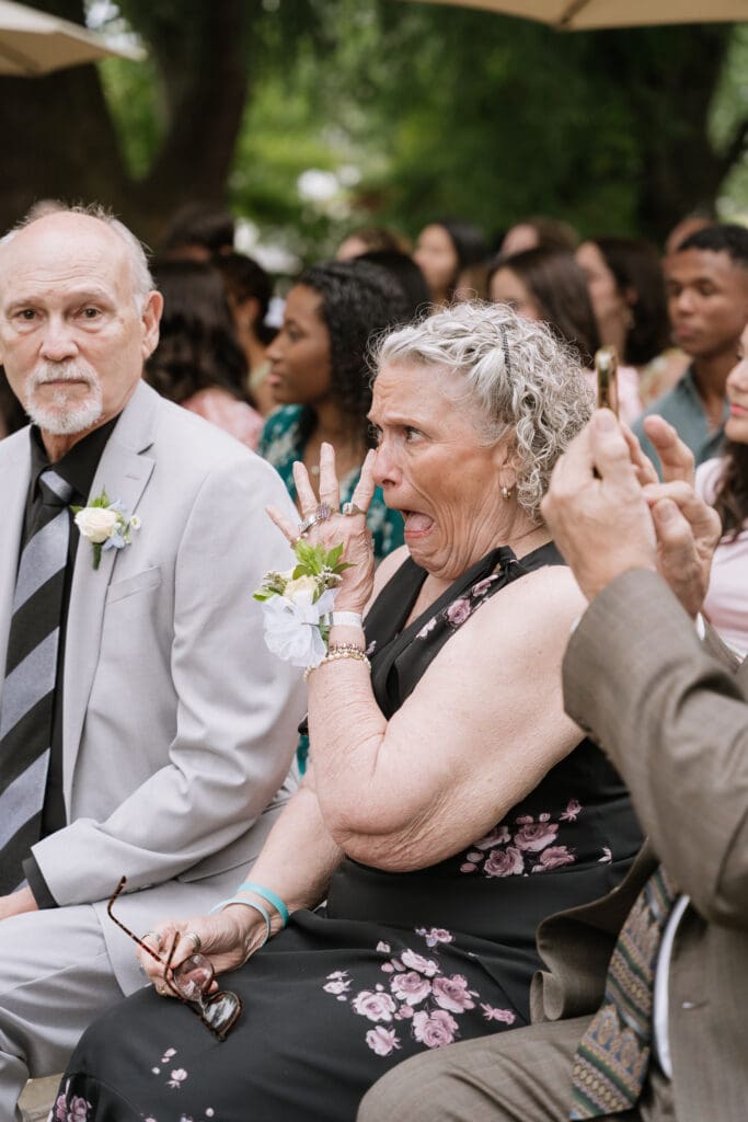 Emotional wedding guest reacting during an outdoor ceremony.