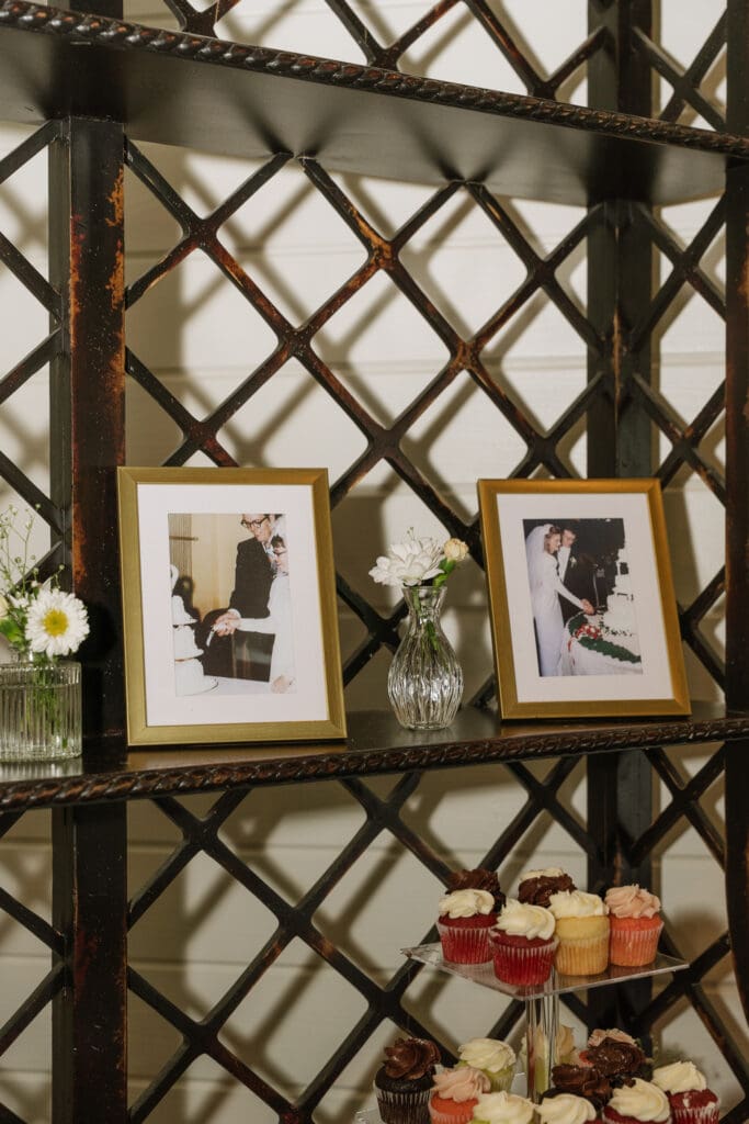 Framed family wedding photographs displayed alongside cupcakes as part of a wedding reception decoration.