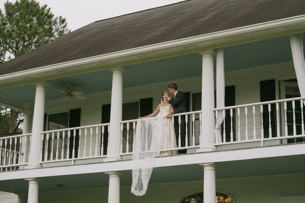 Bride and groom sharing a moment on the balcony of a Southern wedding venue while discussing how shade can improve wedding portraits.